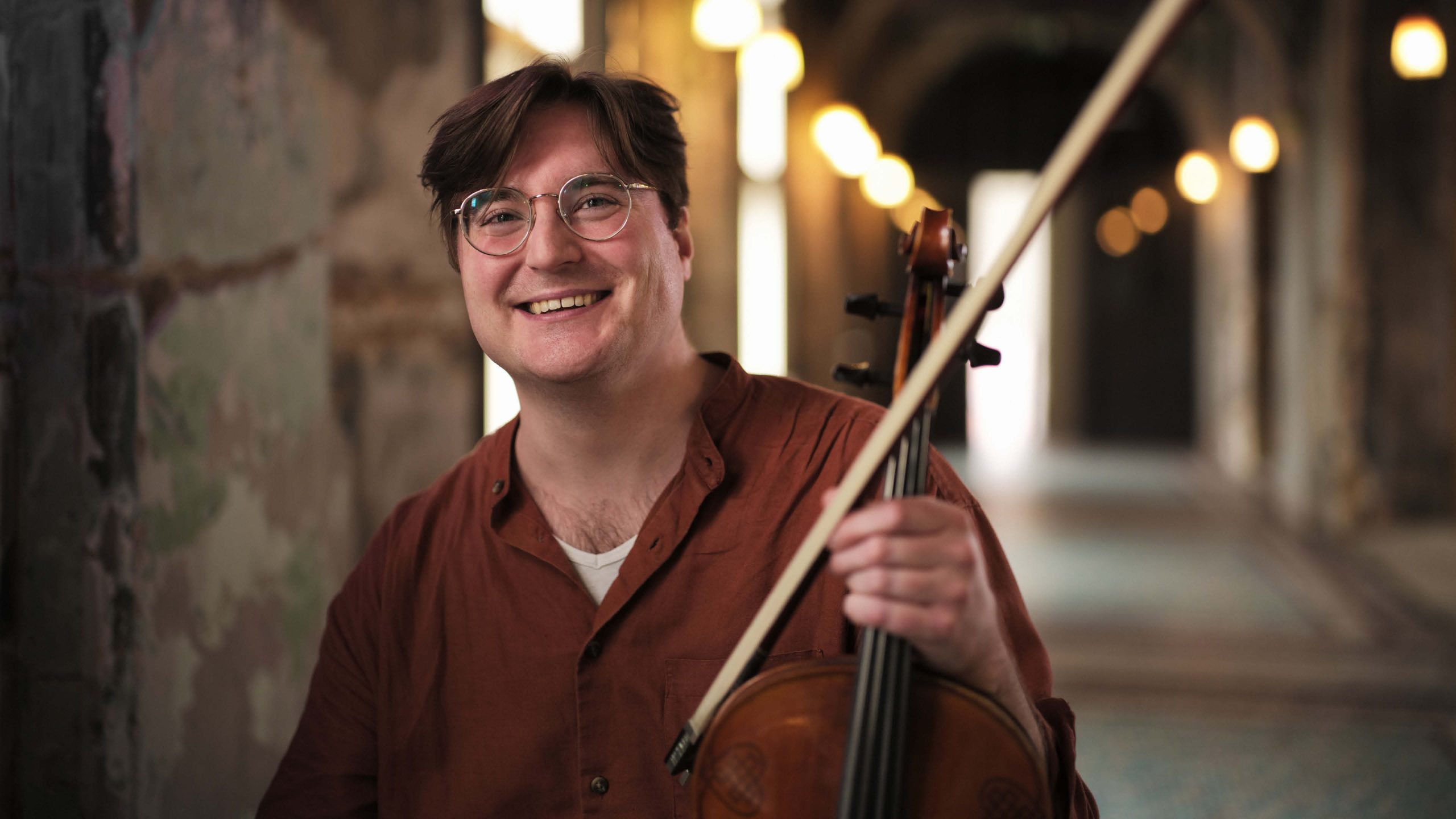Chromatica Orchestra musician holding violin and smiling in a brand design campaign photoshoot. Brand identity by Alphabet Studio